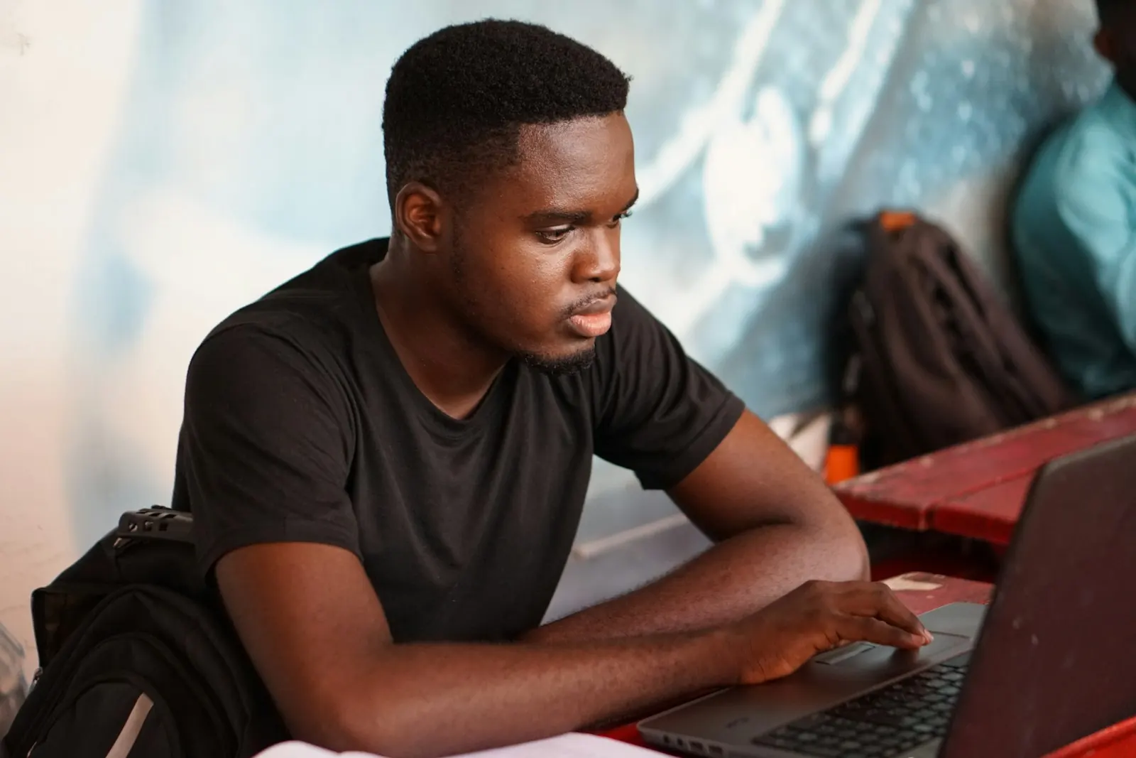 A young man working on a laptop at a university in Kumasi, Ghana